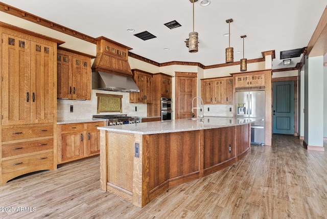 kitchen featuring stainless steel appliances, light wood-style flooring, tasteful backsplash, a spacious island, and custom range hood