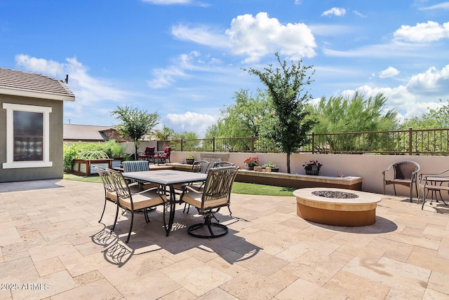 view of patio with a fire pit, outdoor dining space, and fence