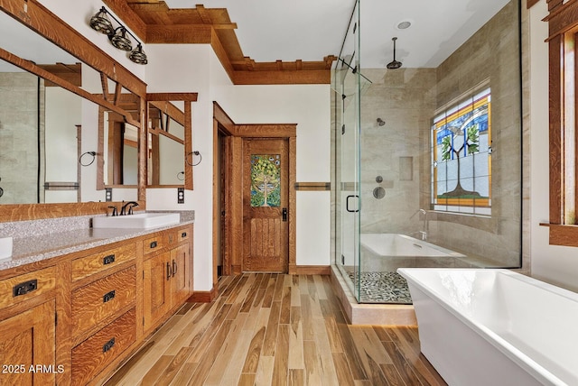 bathroom featuring wood finished floors, a shower stall, a soaking tub, and vanity