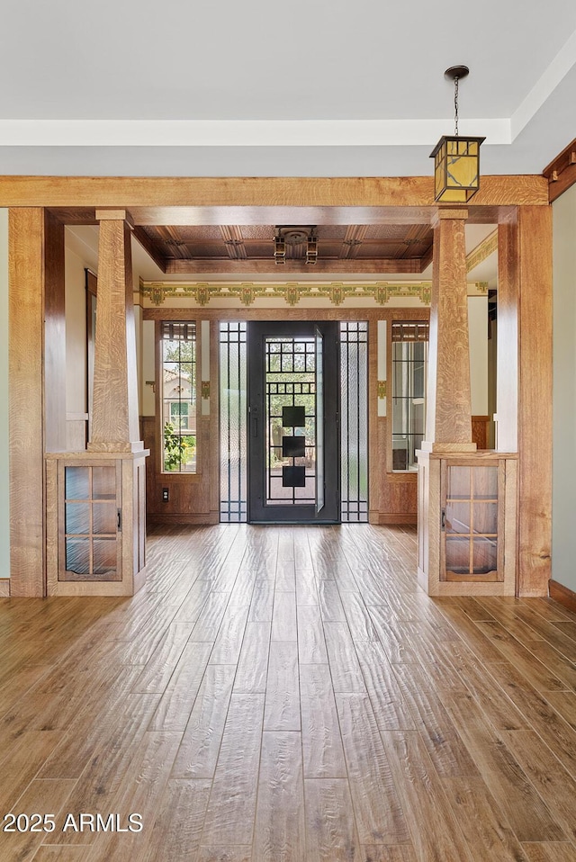 unfurnished living room featuring wood finished floors, decorative columns, beamed ceiling, and baseboards