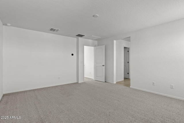 carpeted empty room featuring baseboards, visible vents, and a textured ceiling