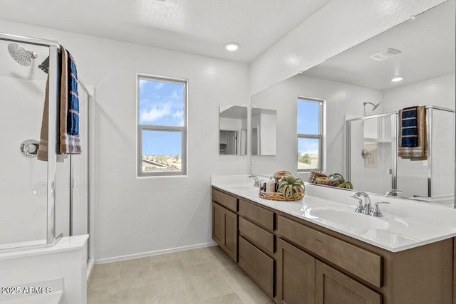 bathroom featuring a sink, a shower stall, baseboards, and double vanity