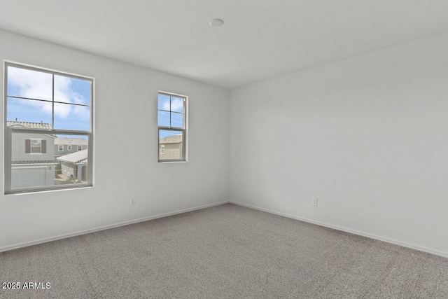 carpeted empty room featuring baseboards