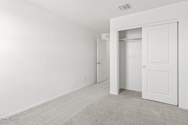 unfurnished bedroom featuring carpet floors, baseboards, visible vents, and a closet