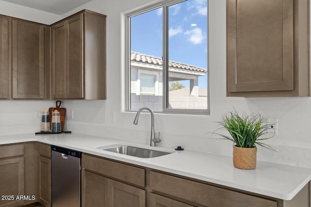 kitchen featuring light countertops, stainless steel dishwasher, and a sink