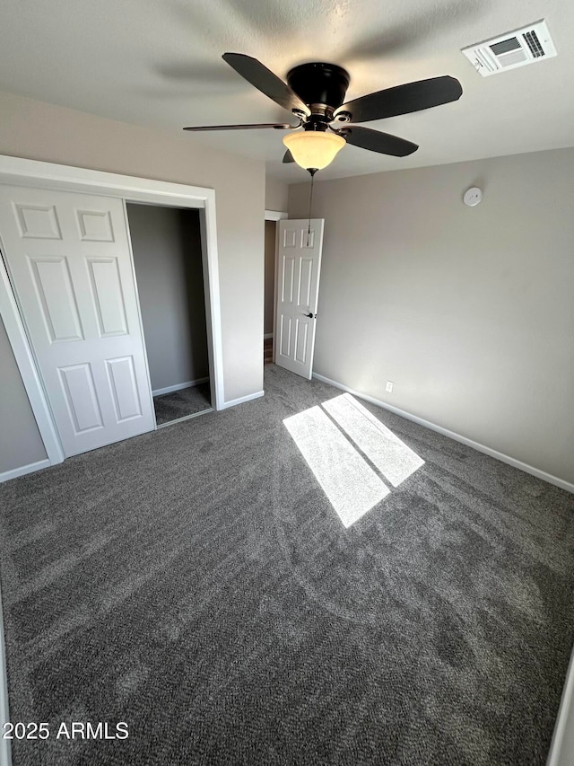 unfurnished bedroom with ceiling fan, a closet, and dark colored carpet