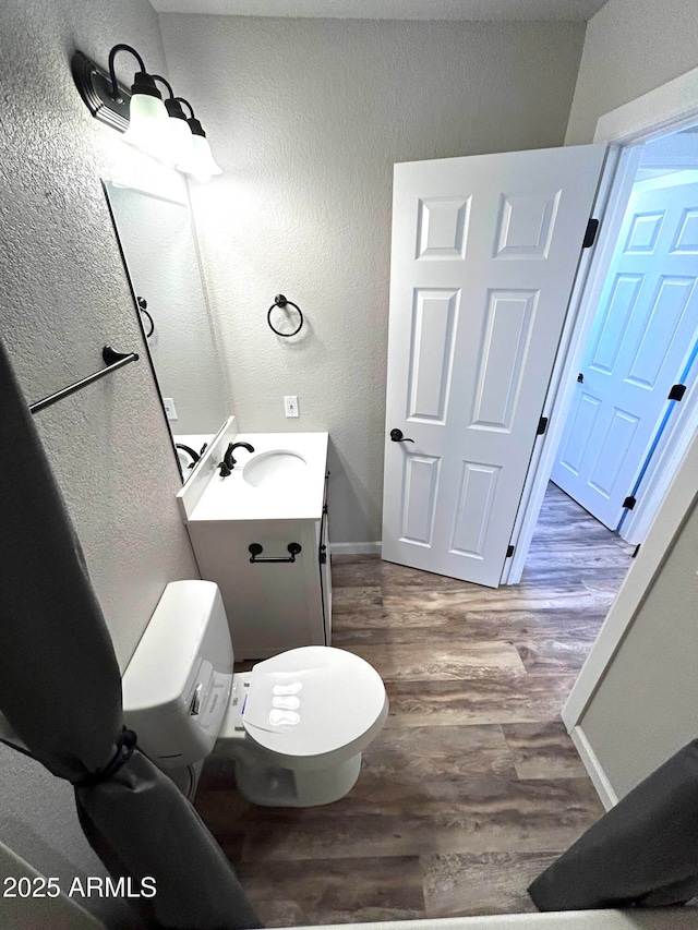 bathroom featuring wood-type flooring, toilet, and vanity