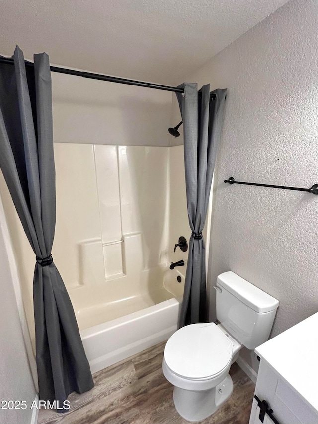 full bathroom featuring toilet, shower / bath combo with shower curtain, a textured ceiling, and hardwood / wood-style floors