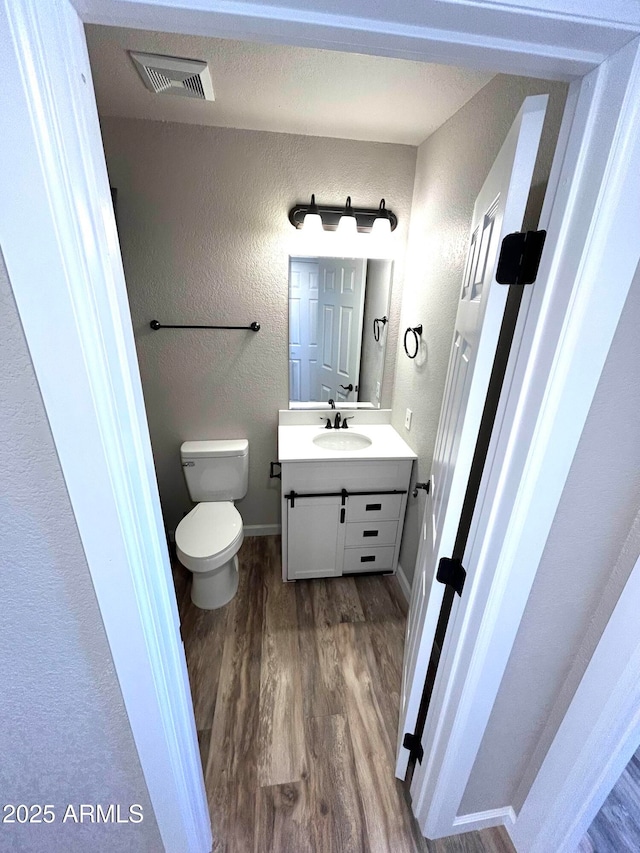 bathroom featuring toilet, vanity, and wood-type flooring