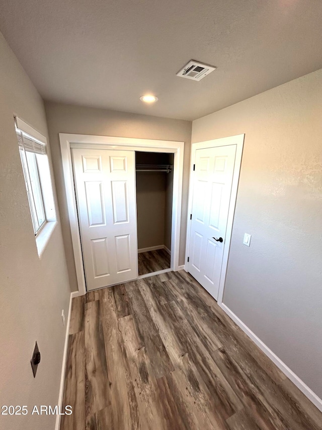 unfurnished bedroom with a closet and dark hardwood / wood-style floors