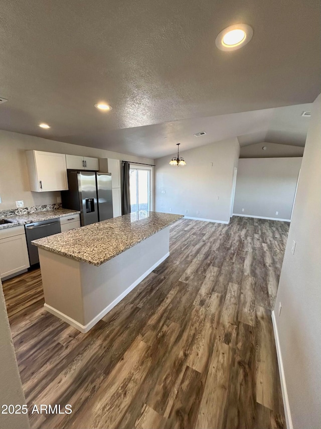 kitchen featuring pendant lighting, a center island, white cabinetry, dishwashing machine, and stainless steel fridge