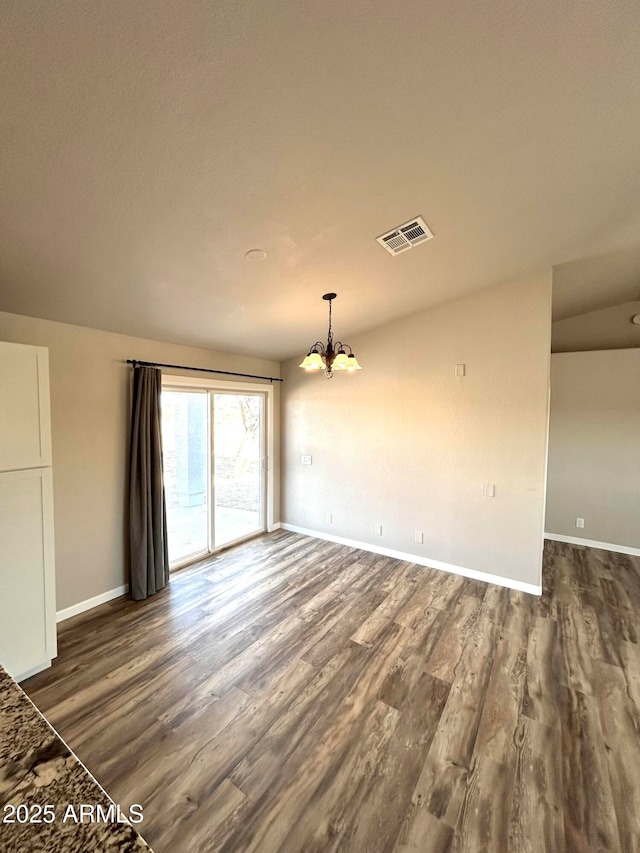 spare room featuring a notable chandelier and dark hardwood / wood-style floors