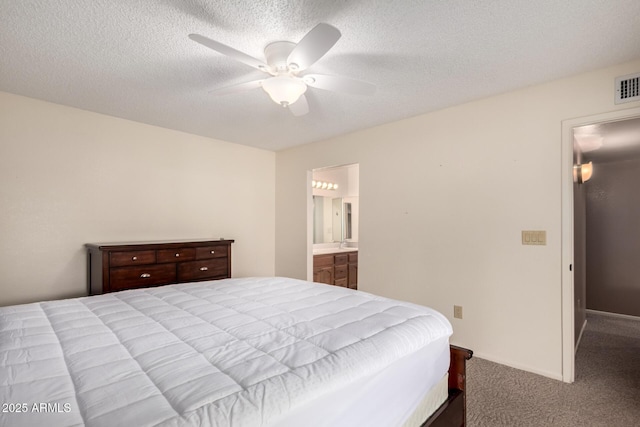 carpeted bedroom featuring visible vents, ensuite bathroom, baseboards, a textured ceiling, and a ceiling fan