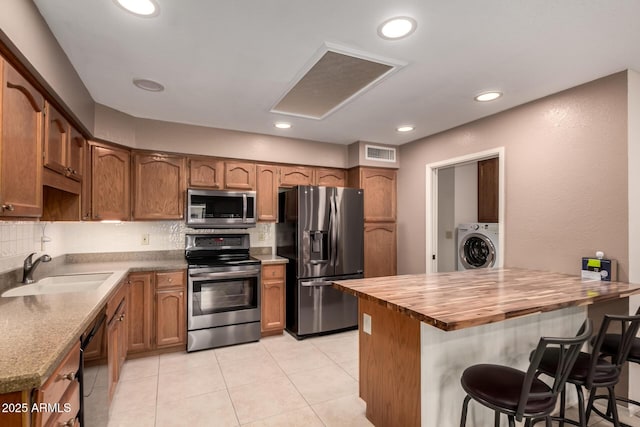 kitchen with visible vents, washer / dryer, wooden counters, a sink, and appliances with stainless steel finishes
