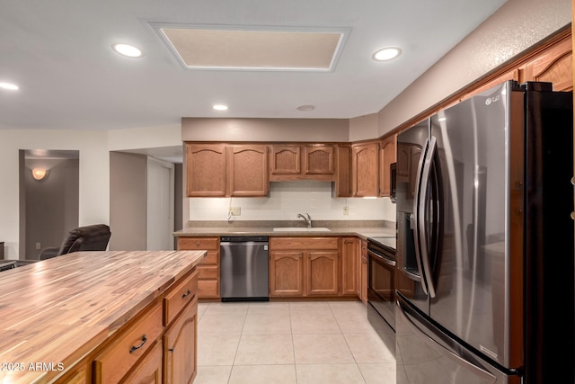 kitchen with stainless steel appliances, brown cabinets, butcher block countertops, and light tile patterned flooring