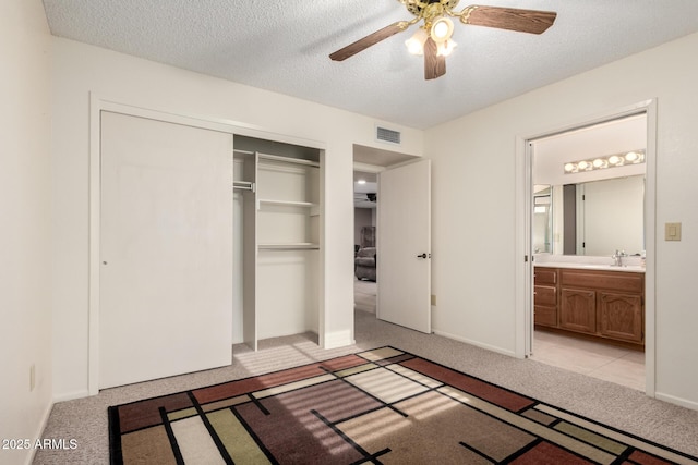 unfurnished bedroom featuring a sink, light carpet, a closet, and visible vents