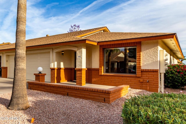 view of front facade featuring concrete driveway, stucco siding, a shingled roof, and a garage