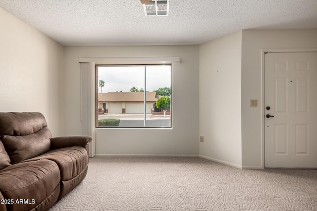 living area featuring a textured ceiling, visible vents, light carpet, and baseboards