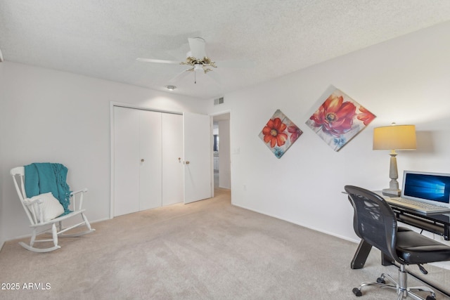 office area featuring light carpet, ceiling fan, and a textured ceiling