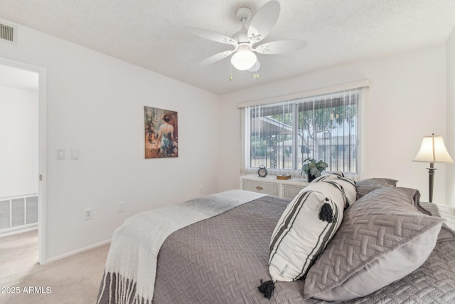 bedroom with a textured ceiling, light colored carpet, and ceiling fan