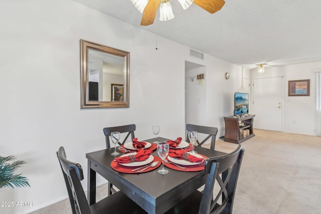 carpeted dining space with ceiling fan and a textured ceiling