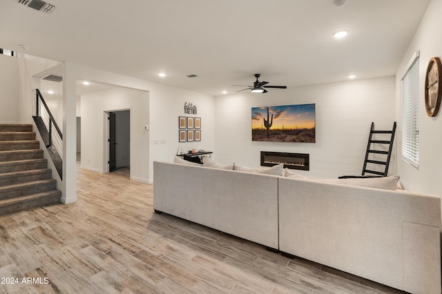 16848 W Alice Ave, Waddell, AZ 85355 - living room featuring a glass covered fireplace, light wood finished floors, ceiling fan, stairway, and recessed lighting