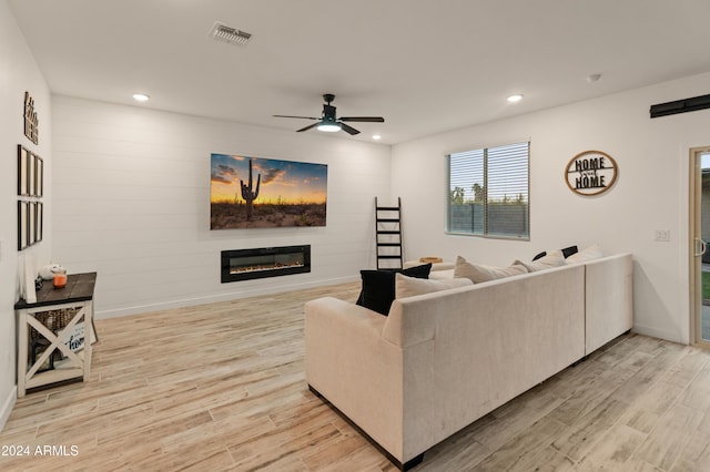 16848 W Alice Ave, Waddell, AZ 85355 - living room with light wood-style flooring, a glass covered fireplace, ceiling fan, recessed lighting, and baseboards