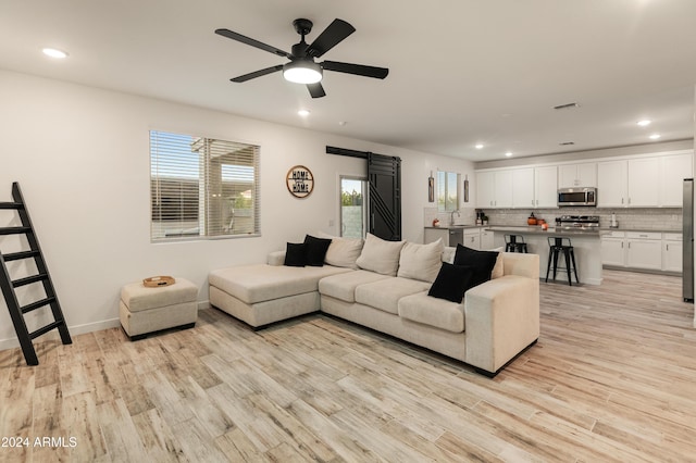 16848 W Alice Ave, Waddell, AZ 85355 - living room with a barn door, light wood-style floors, ceiling fan, recessed lighting, and baseboards