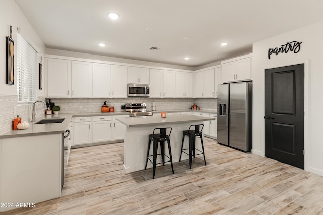 16848 W Alice Ave, Waddell, AZ 85355 - kitchen featuring appliances with stainless steel finishes, a sink, a breakfast bar, backsplash, and a kitchen island