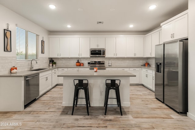 16848 W Alice Ave, Waddell, AZ 85355 - kitchen with stainless steel appliances, a sink, a kitchen island, a breakfast bar area, and white cabinetry