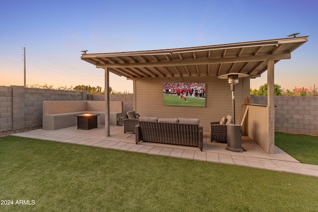 patio terrace at dusk featuring a yard and an outdoor living space with a fire pit