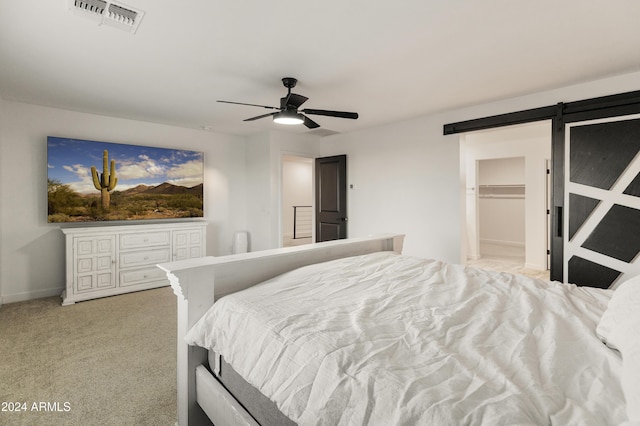 16848 W Alice Ave, Waddell, AZ 85355 - bedroom featuring a barn door, a walk in closet, light colored carpet, and a ceiling fan