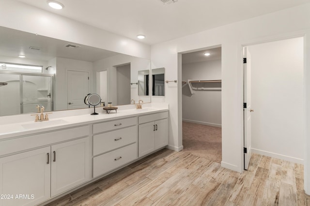 16848 W Alice Ave, Waddell, AZ 85355 - full bathroom with wood finished floors, double vanity, a walk in closet, baseboards, and a shower with door