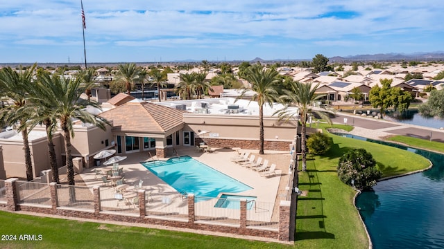 view of swimming pool featuring a yard, a water view, and a patio area