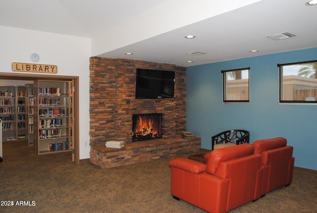 living room featuring a stone fireplace and dark colored carpet