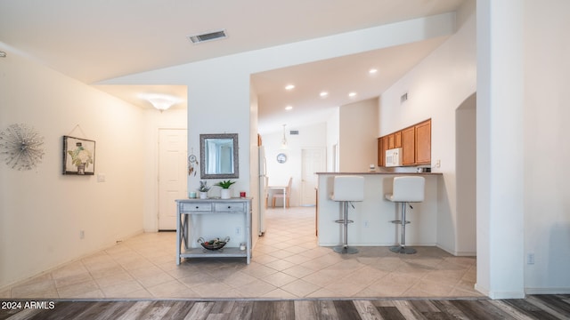 kitchen featuring a kitchen breakfast bar, kitchen peninsula, light wood-type flooring, and lofted ceiling