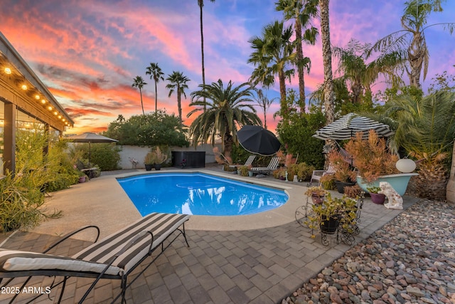 pool at dusk with a patio area