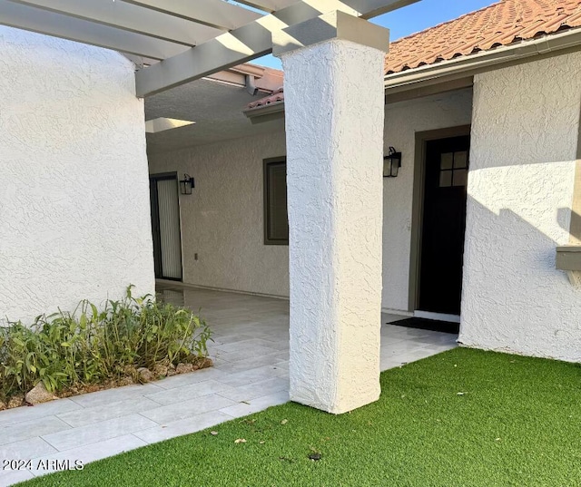 view of exterior entry with a pergola