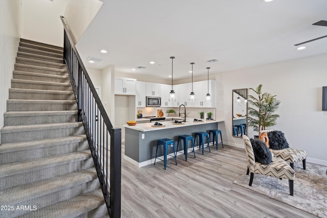 staircase featuring recessed lighting, baseboards, visible vents, and wood finished floors