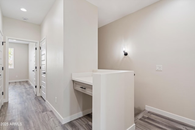 hall featuring light wood-style floors, recessed lighting, baseboards, and an upstairs landing