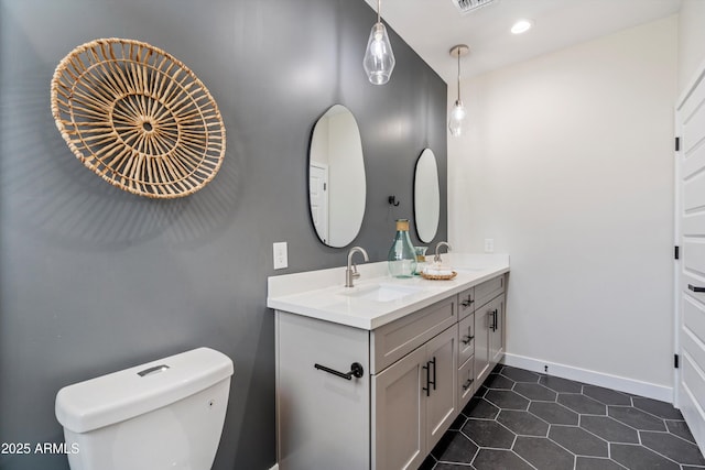 bathroom featuring double vanity, toilet, baseboards, and a sink