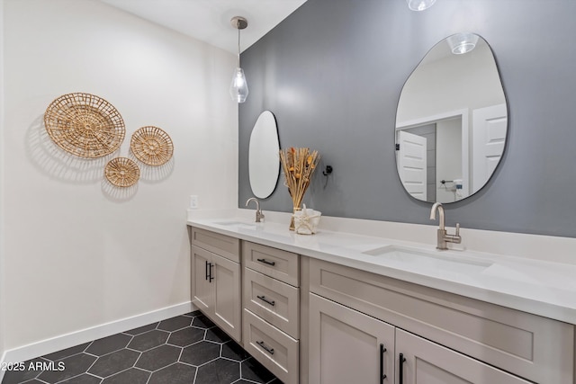 bathroom with double vanity, baseboards, a sink, and tile patterned flooring
