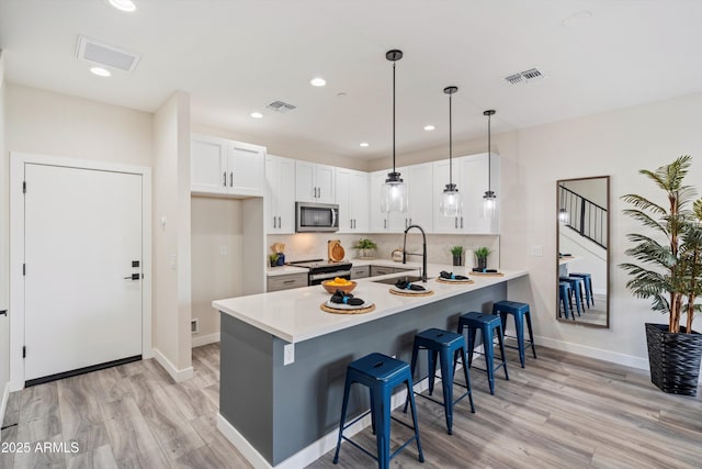 kitchen featuring visible vents, a sink, a peninsula, and stainless steel appliances