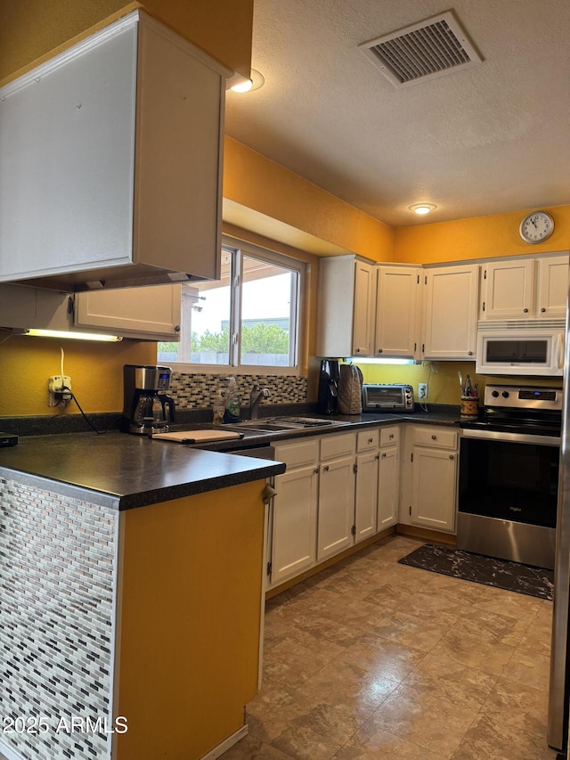 12512 N 85th Ave, Peoria, AZ 85381 - kitchen with white microwave, stainless steel range with electric stovetop, dark countertops, a sink, and white cabinetry
