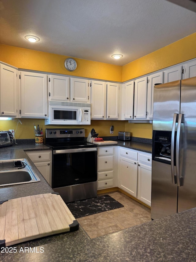 12512 N 85th Ave, Peoria, AZ 85381 - kitchen with stainless steel appliances, white cabinetry, dark countertops, a sink, and recessed lighting