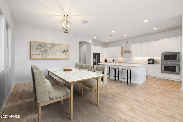 dining area with light wood-type flooring and a chandelier