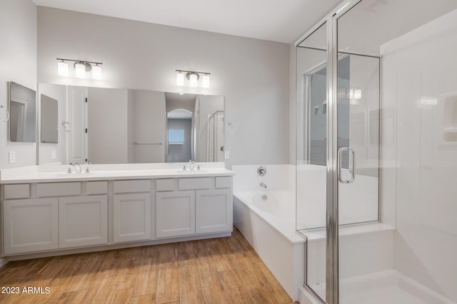 bathroom featuring hardwood / wood-style flooring, separate shower and tub, and double vanity