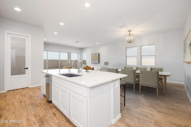 kitchen with a notable chandelier, sink, light hardwood / wood-style flooring, a kitchen island with sink, and white cabinets