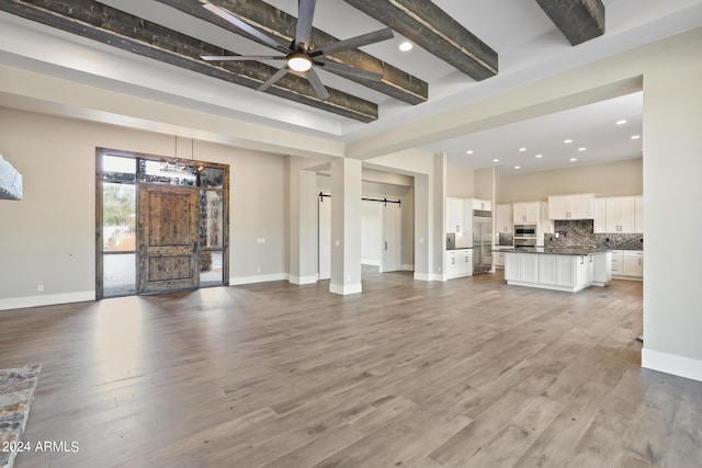 1804 E Senna Pt, Payson, AZ 85541 - unfurnished living room with beamed ceiling, a barn door, baseboards, and wood finished floors