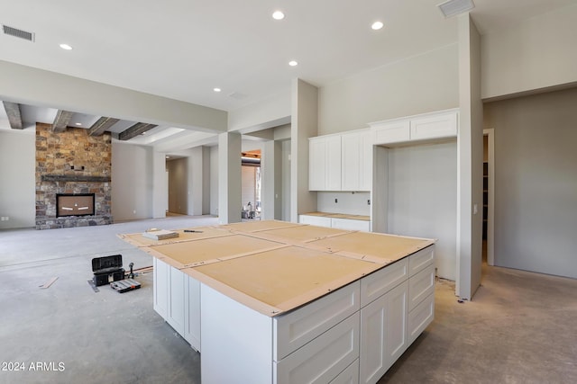 kitchen featuring beam ceiling, a kitchen island, white cabinets, and a fireplace